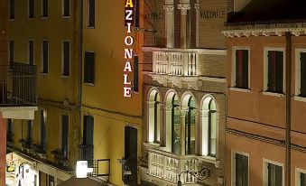 "a nighttime street scene with a building that has the word "" hotel "" on it" at Hotel Nazionale