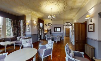 a spacious living room with wooden floors , white walls , and various furniture pieces including chairs , tables , and a couch at Nunsmere Hall Hotel