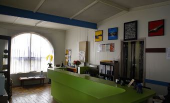 a reception area with a green desk , framed pictures on the wall , and a large window at Charlton Motel