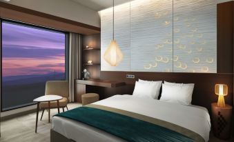 a hotel room with a large bed , a desk , and a window overlooking the ocean at Hotel Metropolitan Akita