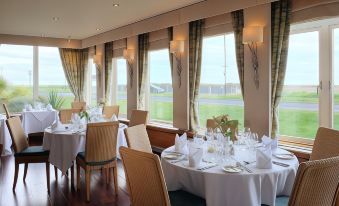 a dining room with tables and chairs set up for a meal , overlooking a grassy field at Wentworth Hotel