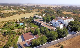 an aerial view of a large white building surrounded by trees and a body of water at Convento do Espinheiro, Historic Hotel & Spa