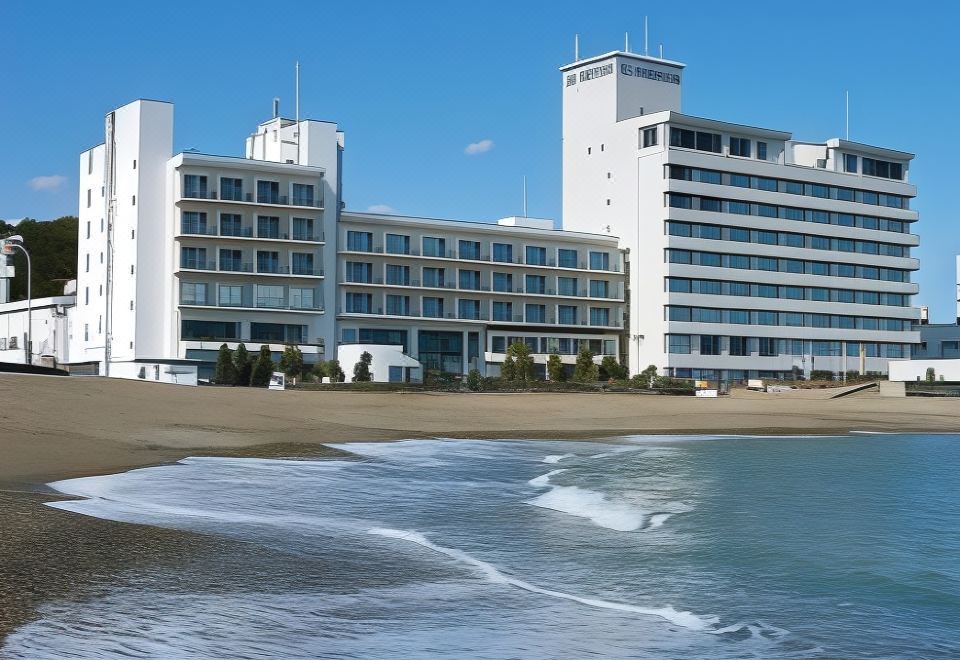 a large white hotel building surrounded by a body of water , with a beach in the background at OARAI HOTEL