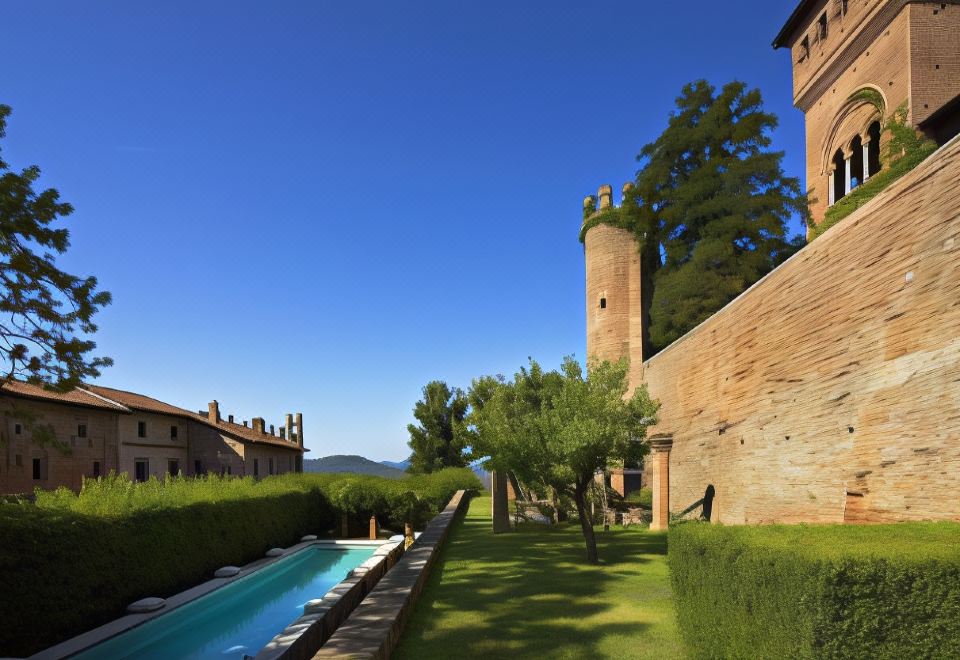 a long , narrow pool is situated next to a brick wall with a tower in the background at Castello di Gabiano