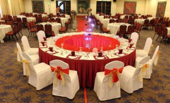 a large round table is set with white chairs and red tablecloths , surrounded by crystal vases at Good Hope Hotel