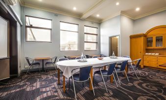 a conference room with a long table , chairs , and large windows is set up for a meeting at Nightcap at Skyways Hotel