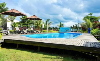 a large wooden deck surrounding a swimming pool , with lounge chairs and umbrellas placed around it at Lakeview Terrace Resort Pengerang
