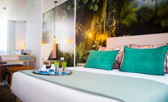 a cozy bedroom with a white bed , green pillows , and a tropical mural on the wall at Thomar Boutique Hotel