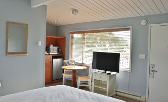 a cozy bedroom with a bed , a desk , and a tv . also a kitchenette visible in the room at Lopez Islander Resort