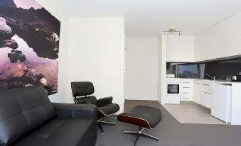 a modern living room with a black leather couch , white chair , and black ottoman at Hotel Launceston