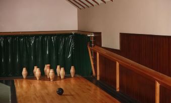 a room with wooden floors and walls , containing several brown vases on the floor and a green curtain in the background at The Brewers Arms
