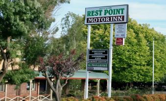 "a sign for the "" rest point motor inn "" with a tree and bushes in the background" at Rest Point Motor Inn