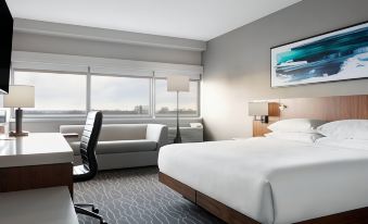 a modern hotel room with a large bed , white bedding , and a view of the city outside the window at Delta Hotels Woodbridge