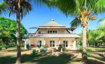 a large , two - story house with a thatched roof is surrounded by palm trees and other greenery at VOI Amarina Resort