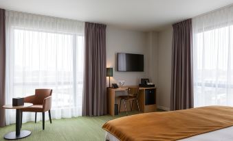 a hotel room with a bed , desk , chair , and tv , along with curtains and curtains covering the window at Best Western Plus Hotel Amstelveen