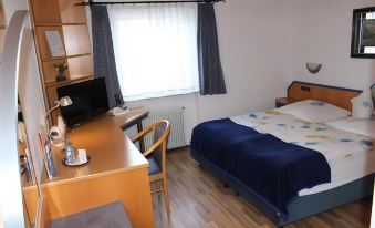 a cozy bedroom with a wooden floor , a bed , and a desk , along with curtains and a window at Hotel Restaurant Post Italia