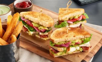 a wooden tray with three different types of sandwiches , including chicken , lettuce , and tomato , accompanied by ketchup and mustard at Courtyard Pasco Tri-Cities Airport