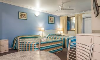 a hotel room with two beds , a dining table , and a fan , all decorated in blue walls and white ceiling at Aspley Carsel Motor Inn