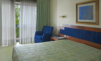 a hotel room with a blue chair , a bed , and a desk , all situated next to each other at Hotel Imperial