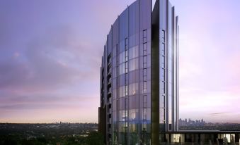 a modern building with a curved facade and large windows is shown against a sunset backdrop at Punthill Ivanhoe