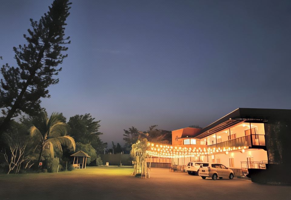 a large , well - lit building with many windows and outdoor lights , surrounded by palm trees at night at Borobudur Bed & Breakfast