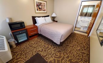 a hotel room with a bed , dresser , and microwave , along with a bathroom visible in the background at Jefferson Hills Motel