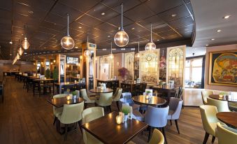 a modern restaurant with wooden tables and chairs , large windows , and hanging lights , giving it an elegant and inviting atmosphere at Crown Inn