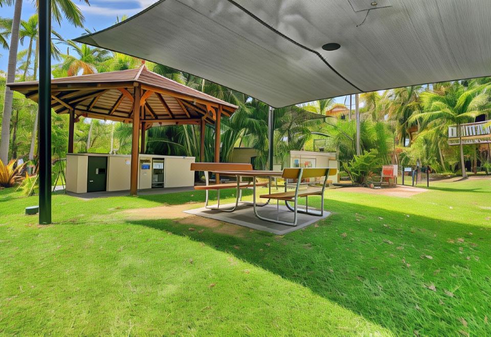 a park with a gazebo and picnic table set up on a grassy area , surrounded by trees at Trinity Links Resort