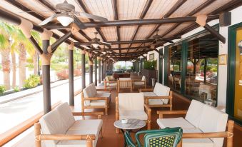 a covered outdoor patio area with several white lounge chairs and umbrellas , providing a relaxing atmosphere at Blue Sea Costa Bastian