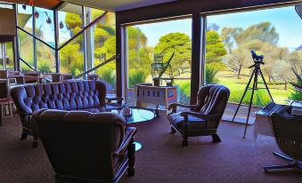 a living room with purple chairs and a couch , surrounded by large windows overlooking a golf course at Renmark Country Club