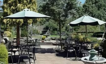 an outdoor dining area with tables and chairs , surrounded by trees and a body of water at The Hood Arms
