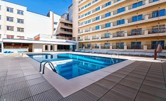 an outdoor swimming pool surrounded by a building , with people enjoying their time in the pool at Hotel Fontana Plaza