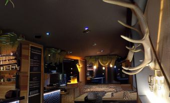 a room with a deer head mounted on the wall , surrounded by various furniture and decorations at Hotel Edelweiss