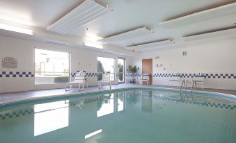an indoor swimming pool surrounded by windows , with several chairs placed around the pool area at Country Inn & Suites by Radisson, Fairview Heights, IL