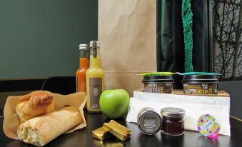 a dining table with a variety of food items , including sandwiches , fruits , and drinks , accompanied by a paper bag at Hotel Izzy