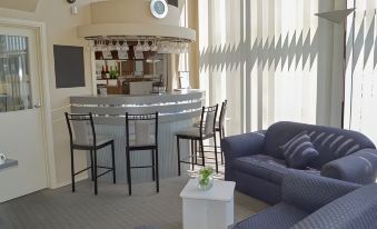 a modern lounge area with a bar , chairs , and a couch in front of large windows at Best Western Mahoneys Motor Inn