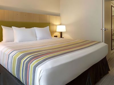 a bed with a white and yellow striped blanket is next to a nightstand with a lamp at Country Inn & Suites by Radisson, Watertown, SD