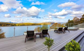 a wooden deck overlooking a body of water , with several chairs placed on it for relaxation at Beech Hill Hotel & Spa