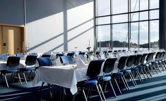 a long table with a white tablecloth and blue chairs is set up in a room with large windows at Son Spa, an Ascend Member