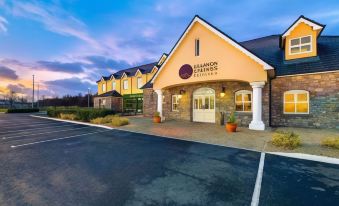 a large hotel with a pink and white exterior , surrounded by trees and a parking lot at Shannon Springs Hotel