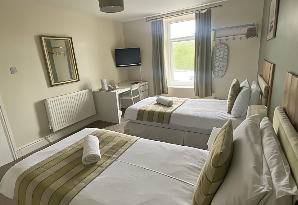 a hotel room with two beds , a window , and a tv , all neatly arranged on white beds at Number 19 Guest House - 4 Miles from Barrow in Furness - 1 Mile from Safari Zoo