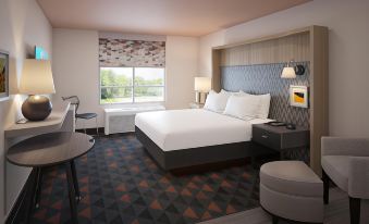 a modern hotel room with a large bed , two nightstands , and a desk , along with a view of the city through a window at Holiday Inn & Suites Hopkinsville - Convention Ctr