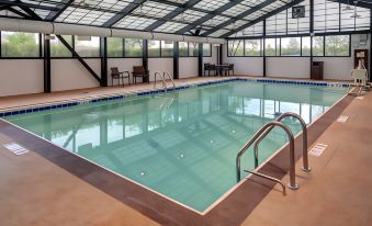 a large swimming pool with a silver handrail and lounge chairs is surrounded by windows at Hyatt Place Pittsburgh Airport/Robinson Mall