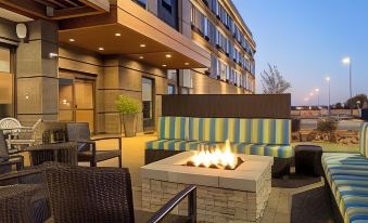 a fire pit is located in the middle of a patio with striped couches and chairs at Home2 Suites by Hilton Gonzales