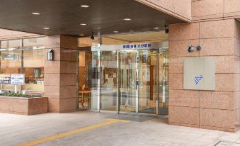 a modern building with an entrance that has glass doors and a sign in chinese at Toyoko Inn Oita Ekimae