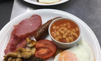 a dining table with two plates of food , one containing a variety of meats and vegetables , and the other containing eggs , beans , mushrooms , at The Garret