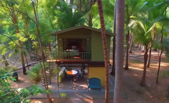 a small , green house surrounded by trees , with a table and chairs on the porch at Puerto Barillas