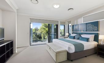 a modern bedroom with a large bed , white walls , and a sliding glass door leading to a balcony at Sand Dunes Resort