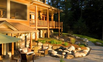 a large wooden house with a patio and outdoor furniture , surrounded by trees and rocks at The Fern Lodge