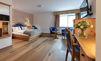 a modern hotel room with a large bed , wooden floors , and blue accents , as well as a desk area at Hotel Cristallo